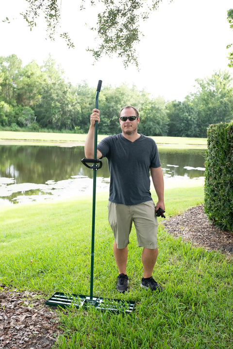Man holding Heavy Duty Lawn Leveling Rake With 30x10 Inch Head And Anti Flip Design by a pond on grass with ergonomic grip