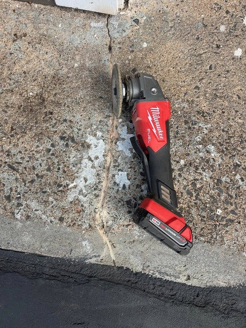 Concrete surface with visible crack and power tool on top, showing repair process for 2X Concrete Crack Sealant Easy To Use No Mess Ready Mixed Filler For Cracks Up To Half Inch Self Leveling Gray Finish Traffic Ready In 30 To 45 Minutes Ideal For Driveways Patios And Concrete Surfaces