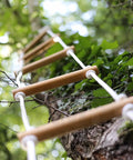 Rope ladder using Paracord 550 Nylon Rope For Camping And Hiking, hanging from tree in forest, showcasing durability