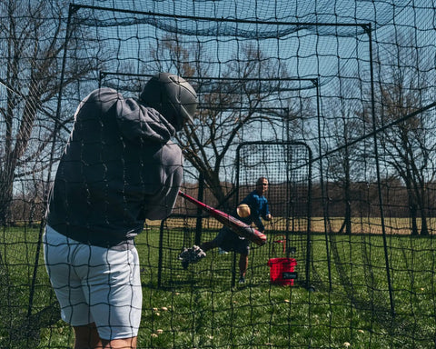 Person batting inside 40 Ft Baseball Softball Batting Cage With Black Steel Frame And 60 Ply Net, perfect backyard setup