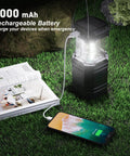 Hand Crank Solar Camping Lantern With 3000mAh Battery, Ultra Bright LED Torch, USB Rechargeable next to phone charging on grass