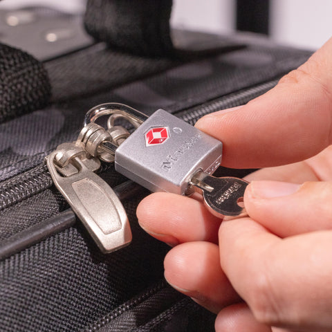 Hand using key on brass TSA luggage lock with keyed padlocks for backpacks and suitcases TSA approved travel security lock for zippers 4 pack keeps your bags locked and ready to roll.