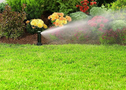Gear Drive Sprinklers Are A Total Game Changer For Patchy Lawns, multi rotor heads watering green lawn with flowers nearby.