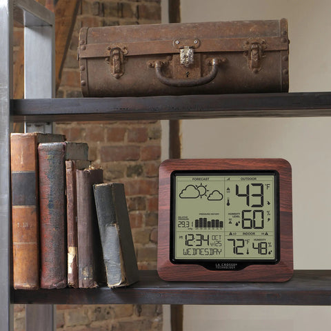 Backlit Wireless Forecast Weather Station With Pressure And Temp Trends Indoor Outdoor Temp Humidity 24 Hour Pressure History Temperature Alerts And Continuous Display on shelf with books and suitcase.
