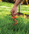 Person installing Heavy Duty 8 Inch Spiral Ground Anchor With Folding Ring Screw In Steel For 125 Lb Pull Weatherproof Powder Coated Orange