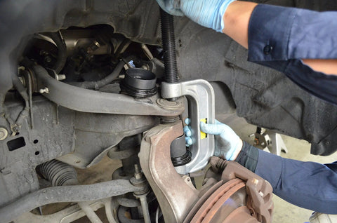 Astro Pneumatic ball joint press tool in use on automotive suspension; silver C-frame with adapters