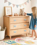 Blue Bow Dresser Knobs 4 Pack Small Decorative Cabinet Drawer Pull Handles For Girls Bedroom And Nursery Decor Two Size Options With Screws And Washers Included Easy To Install Vintage Cute Home Hardware on a wooden dresser in a child's room.