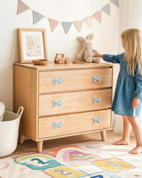 Blue Bow Dresser Knobs 4 Pack Small Decorative Cabinet Drawer Pull Handles For Girls Bedroom And Nursery Decor Two Size Options With Screws And Washers Included Easy To Install Vintage Cute Home Hardware on a wooden dresser in a child's room.
