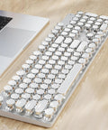 Wireless Typewriter Style Mechanical Keyboard With Clicky Blue Switches And Crisp White Backlighting on a desk beside a laptop.