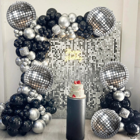 Showstopping 22 Inch Silver Disco Balloons Pack of 6 4D Sphere Balloons for Disco Party Decorations Retro 70s Theme Birthday Anniversary Decor and Photo Backdrops for Lit Party Vibes arranged with black and silver balloons around cake backdrop.