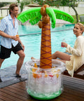 Inflatable Palm Tree Cooler, 60 Inch Tall, Beach Theme Pool Party Decor with ice and drinks near a poolside.