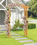Arched-Top Wooden Garden Arch For Outdoor Use, 7.5 Ft Tall Trellis Arbor covered in pink roses, in a garden setting near a white house.