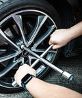Hands using Heavy Duty Four Way Universal Cross Lug Wrench Tire Iron on a car wheel, showcasing its 14 inch length and chrome plated finish.