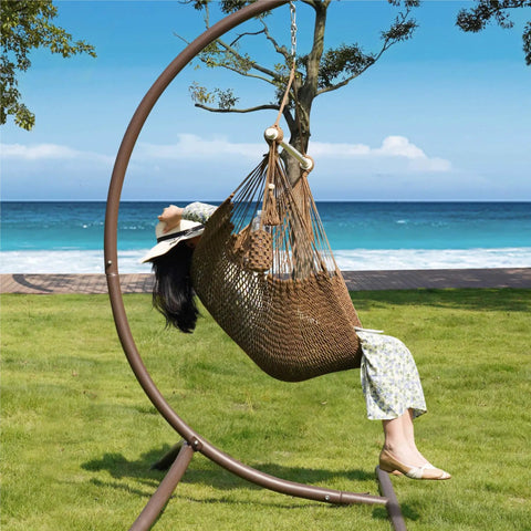 Person relaxing in a Caribbean Style Rope Hammock Chair with 40 Inch Steel Spreader Bar and anti slip rings in a garden setting