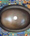 16 By 13 Inch Oval Skirted Vessel Copper Sink Hand Hammered Pure Copper Brown Finish For Modern Bath Semi Recessed Vessel One And A Half Inch Drain Opening Eighteen Gauge Handmade In Mexico CPS10, top view
