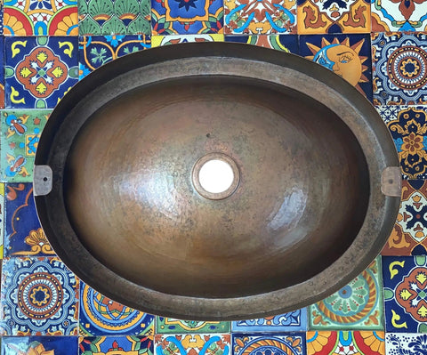 16 By 13 Inch Oval Skirted Vessel Copper Sink Hand Hammered Pure Copper Brown Finish For Modern Bath Semi Recessed Vessel One And A Half Inch Drain Opening Eighteen Gauge Handmade In Mexico CPS10, top view