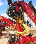 Yellow Safe-Spiral Pre-Cut Hose And Cable Protector Wrap on red hydraulic machinery at outdoor industrial site