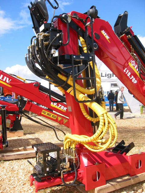 Yellow Safe-Spiral Pre-Cut Hose And Cable Protector Wrap on red hydraulic machinery at outdoor industrial site