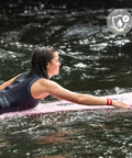 Woman surfing with adjustable wrist brace for TFCC tears, water friendly, supporting radius and ulna, all day comfort during sports.