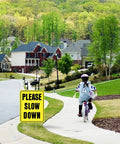 Please Slow Down Yard Sign With Stake 13x17 Inches Double Sided Corrugated Plastic installed on suburban street for safety.