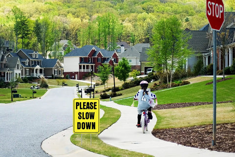 Please Slow Down Yard Sign With Stake 13x17 Inches Double Sided Corrugated Plastic installed on suburban street for safety.