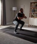 Man exercising on 4x8 Gym Flooring Mat For Peloton Bike Elliptical Treadmill And Home Gym Setup Non Slip Floor Pad For Hardwood Or Carpet
