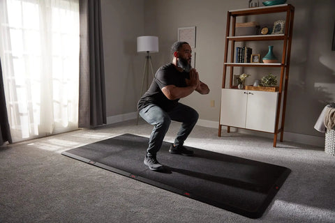 Man exercising on 4x8 Gym Flooring Mat For Peloton Bike Elliptical Treadmill And Home Gym Setup Non Slip Floor Pad For Hardwood Or Carpet