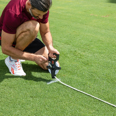 Person using Open Reel Measuring Tape With Hand Crank And Metal Spike Durable Fiberglass Tape Dual Sided Feet And Meters