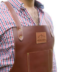 Person wearing Leather Grill Master Apron With Cross Back Straps Heat Resistant Full Grain Leather For BBQ Woodworking Barber And Welding