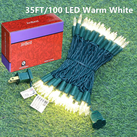 Bundle of 100 LED Warm White Christmas String Lights With 35 Ft White Wire, UL Certified, next to branded red box on grass