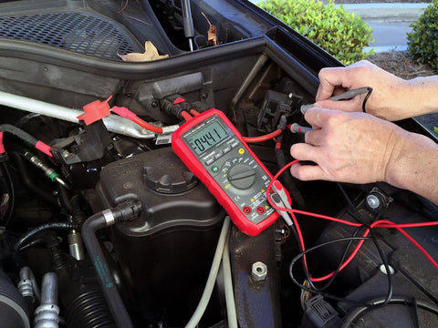 Using Auto Range Digital Multimeter With NCV, Backlit LCD for car diagnostics, connected to engine bay showing 9.041 reading.