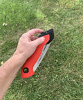 7 Inch Folding Pruning Saw With Fast Cut Razor Tooth Blade Heavy Duty Hand Tool held in hand over grass for tree branch trimming.