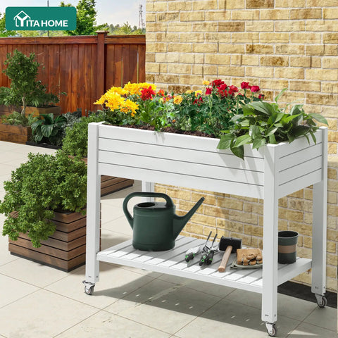 Elevated Garden Bed Kit With Legs And Wheels Large Resin Planter Box Stand With Drain Plug And Storage Shelf Perfect For Plants Vegetables Fruits Outdoor Durable Grayish White on patio filled with colorful flowers.