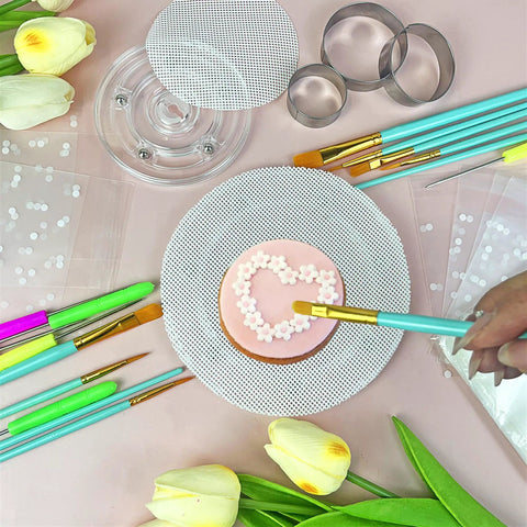 Decorating a cookie with a brush on a non-slip silicone mat in a 123 Piece Cookie Decorating Kit With Large Acrylic Turntables.