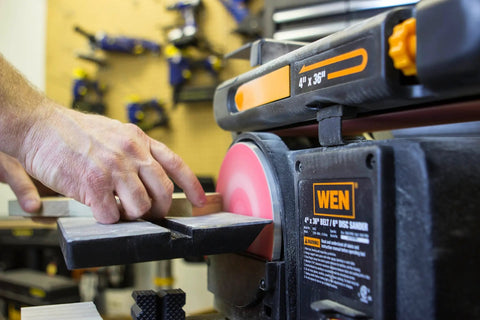 User operates Two In One Benchtop Belt And Disc Sander For The Home Workshop With Four By Thirty Six Inch Belt And Six By Six Inch Disc