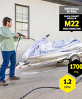 Man using Compact 1700 PSI TruPressure Pressure Washer With 1.2 GPM to clean a jet ski on driveway, featuring hose connection.