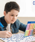Child using 11 By 14 Dry Erase Multiplication Chart Whiteboard for homeschool math practice, holding colorful multiplication card.