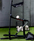 All In One Baseball And Softball Training Aid With Spring Loaded Ball Launcher For Batting And Grounders Battery Free Pitching Machine for backyard practice, featuring gray spring-powered device loaded with baseballs on green turf