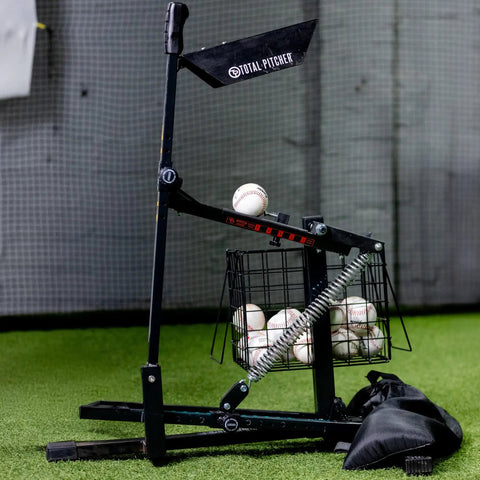 All In One Baseball And Softball Training Aid With Spring Loaded Ball Launcher For Batting And Grounders Battery Free Pitching Machine for backyard practice, featuring gray spring-powered device loaded with baseballs on green turf