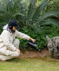 Person using Handheld Seed Spreader For Lawn And Garden, Adjustable Shaker For Fertilizer, 2.5 Liter Capacity in a garden