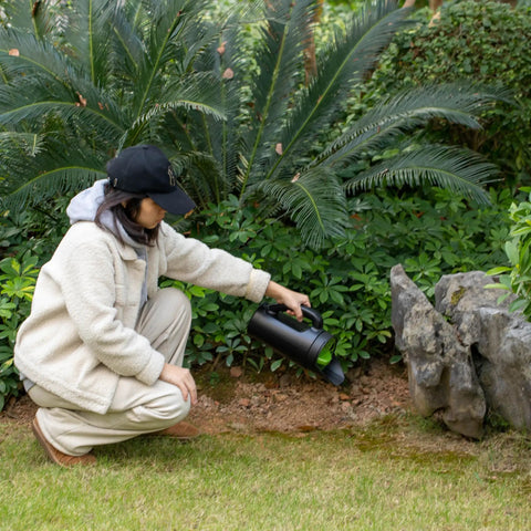 Person using Handheld Seed Spreader For Lawn And Garden, Adjustable Shaker For Fertilizer, 2.5 Liter Capacity in a garden