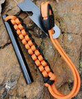 Drilled Ferro Rod Fire Starter Kit with 4 Inch Flint Steel Paracord Lanyard Handle Striker and Whistle on rock surface