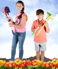 Kids holding Kids Garden Tool Set 4 Piece Shovel Rake Hoe Leaf Rake Wooden Gardening Tools For Kids in a garden setting.
