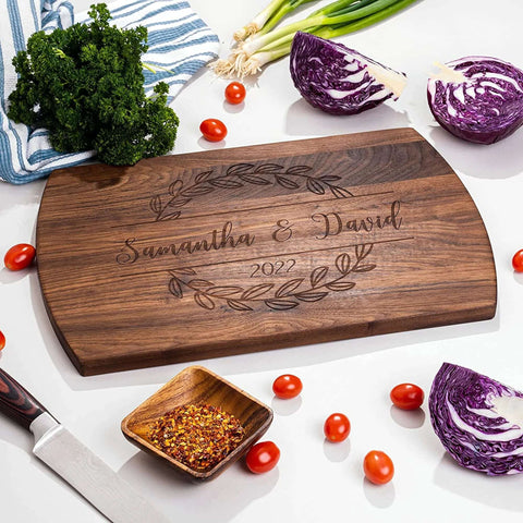 Front view: Wooden cutting board with dark wood finish, laser-engraved Samantha & David and 2022, laurel border.