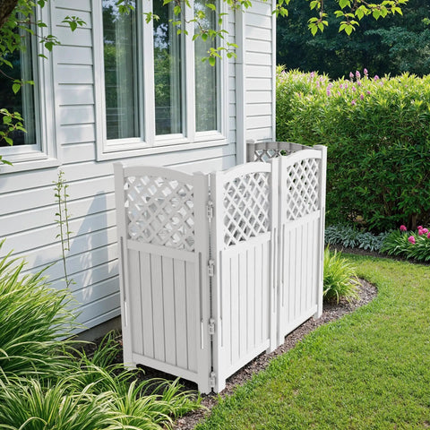 Off white outdoor privacy fence screen with lattice mesh panels concealing air conditioners and pool equipment by a house wall in a garden.
