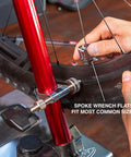 Hand using 4 In 1 Bicycle Spoke Wrench Kit With 3 Spoke Nipples Tools Plus Valve Core Remover And Valve Extender Holder for repairs