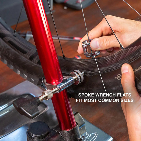Hand using 4 In 1 Bicycle Spoke Wrench Kit With 3 Spoke Nipples Tools Plus Valve Core Remover And Valve Extender Holder for repairs