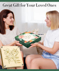 Two women exchanging a 11x11 Inch 10 Layer Flower Press Kit for DIY crafts pressed flowers, featuring a floral design on the package.