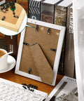 Back view of white picture frame with metal turn-button fasteners and screws for hanging photos.