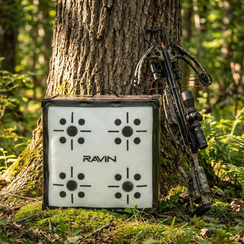 650 FPS Ravin Edition Crossbow Target For Archery Ultra High Speed Stop With Aramid Core Technology beside a tree with crossbow.